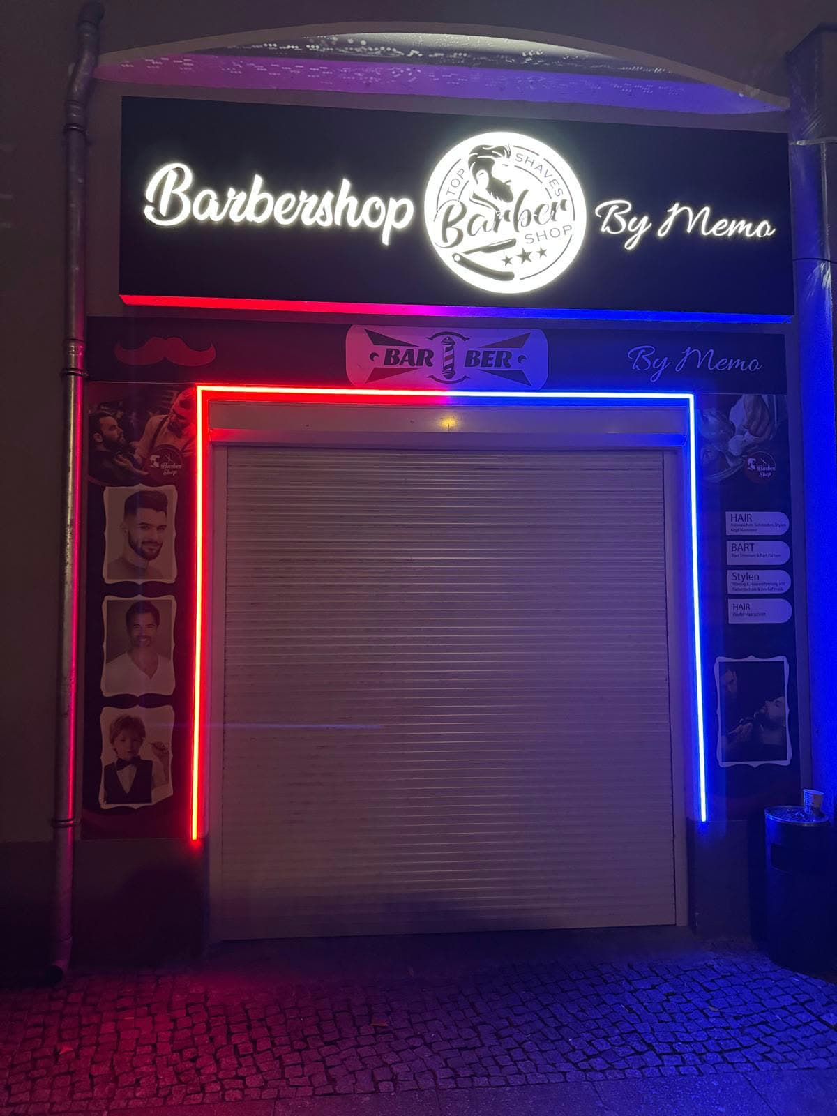 Beleuchtete Ladenfront von Barbershop by Memo bei Nacht in der Hechelstraße 2, Berlin-Reinickendorf – Leuchtschild und Neon in Barber-Pole-Farben